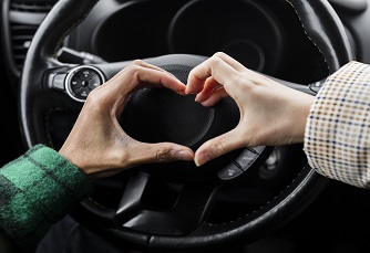 jovem casal viajando de carro fecha fazendo formato de coração