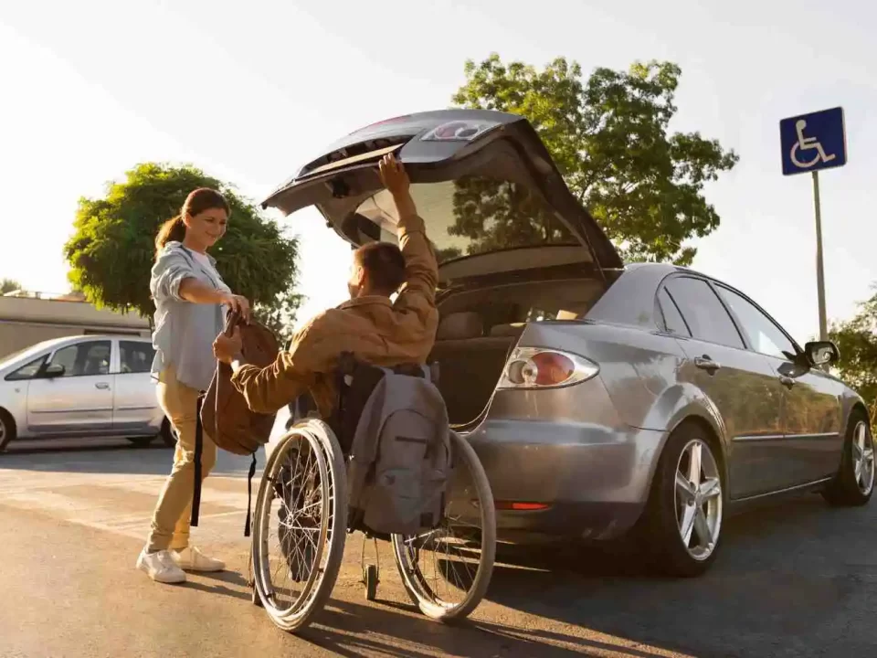 Imagem com um carro e duas pessoas, sendo uma delas um cadeirante passando a mochila para a outra pessoa.