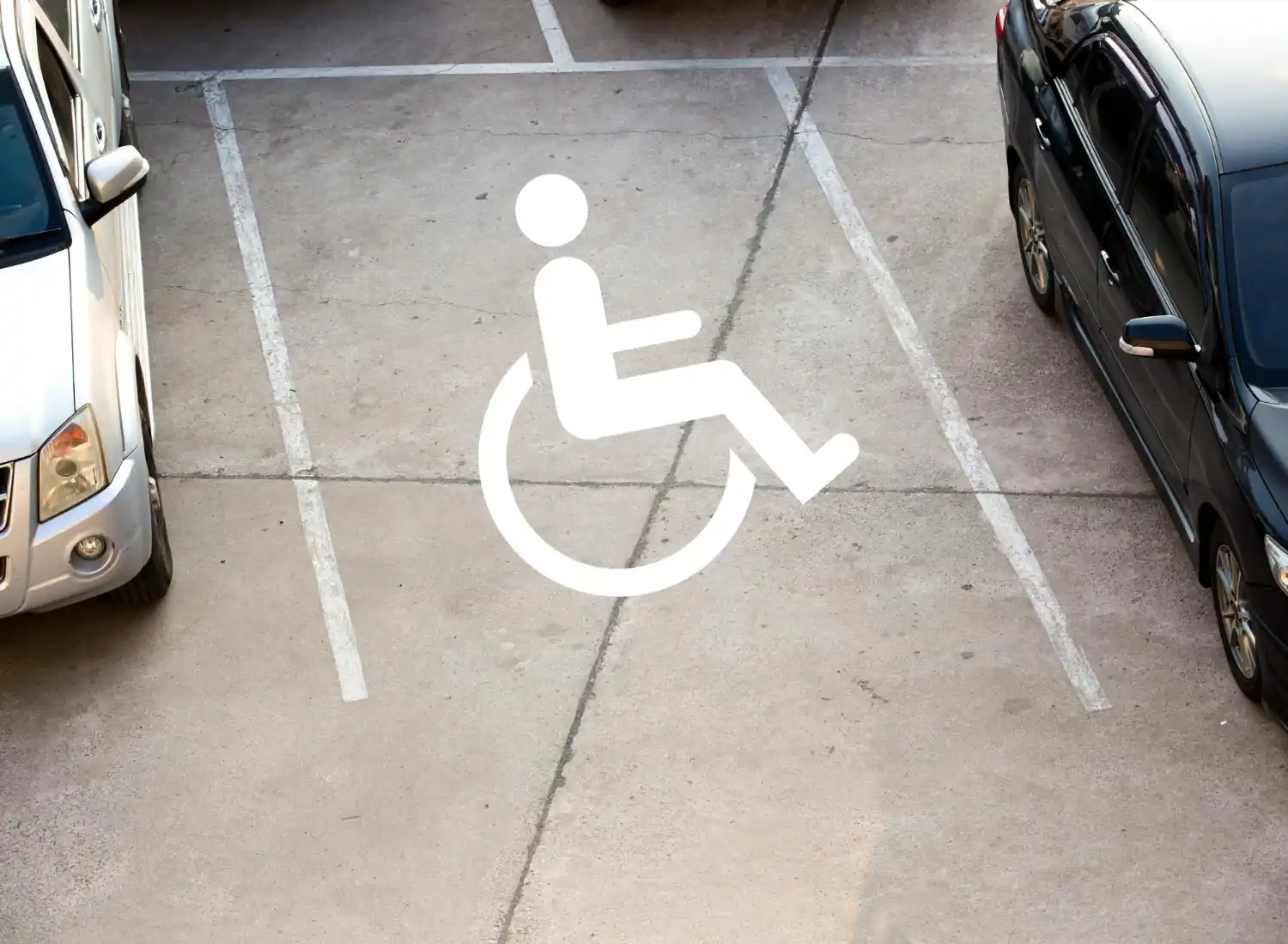 Vaga de estacionamento PCD com símbolo de acessibilidade e carros ao lado